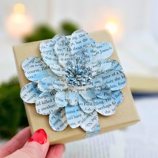 3.5 x 3.5 inch jewelry gift box adorned with a flower made from book pages.  It is stained blue and has silver sparkly on the edges.