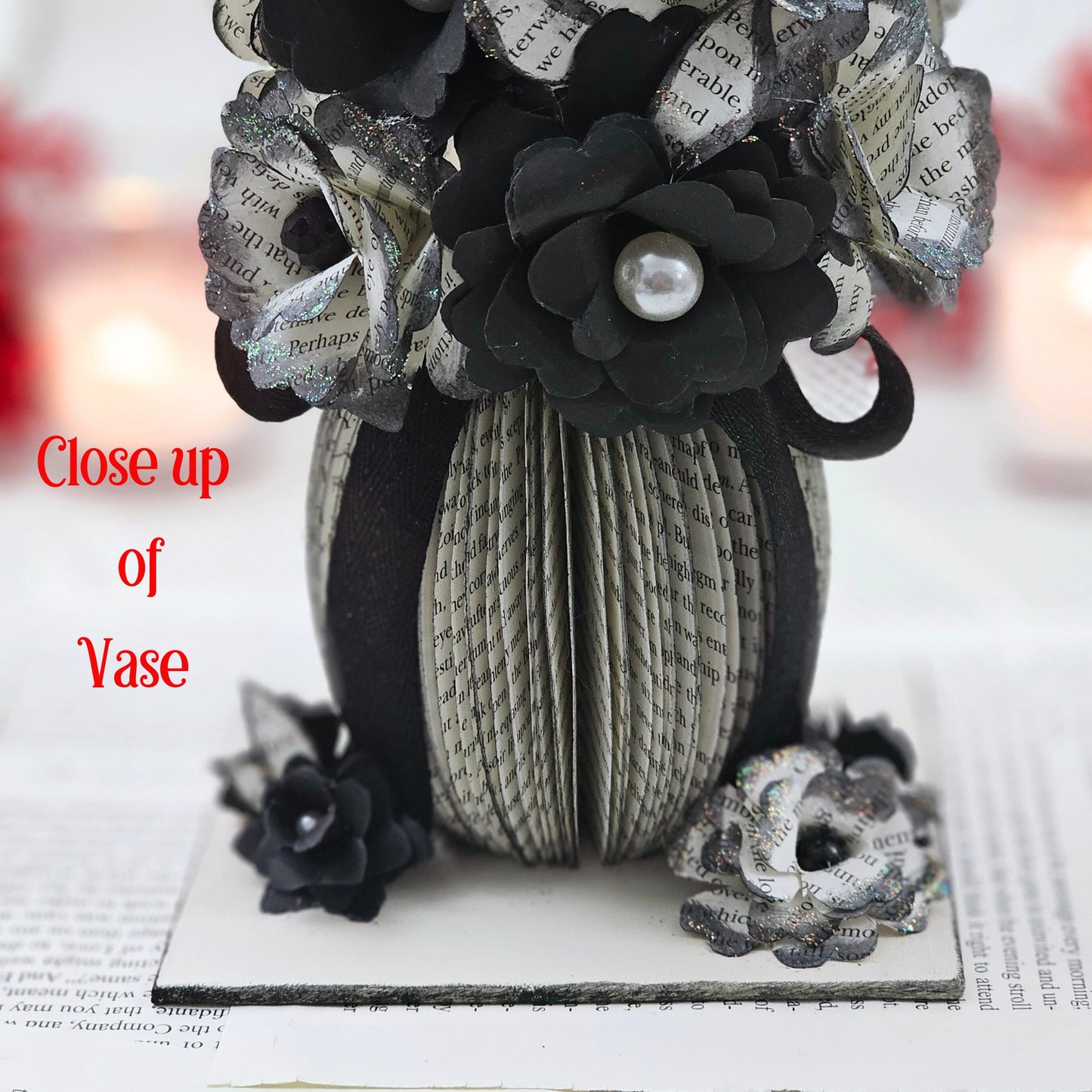 Close up picture of the base and the vase of the arrangement. The vase is made from book pages.