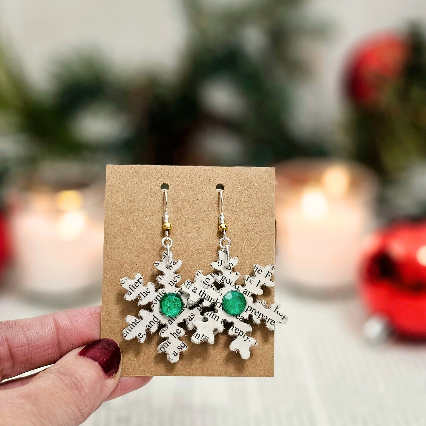 Snow flake dangle earrings made from book pages, they come ready to gift in a book page envelope. Earrings measure 1.5x1.5 inches and have a green acrylic accent on each side of the snowflakes.