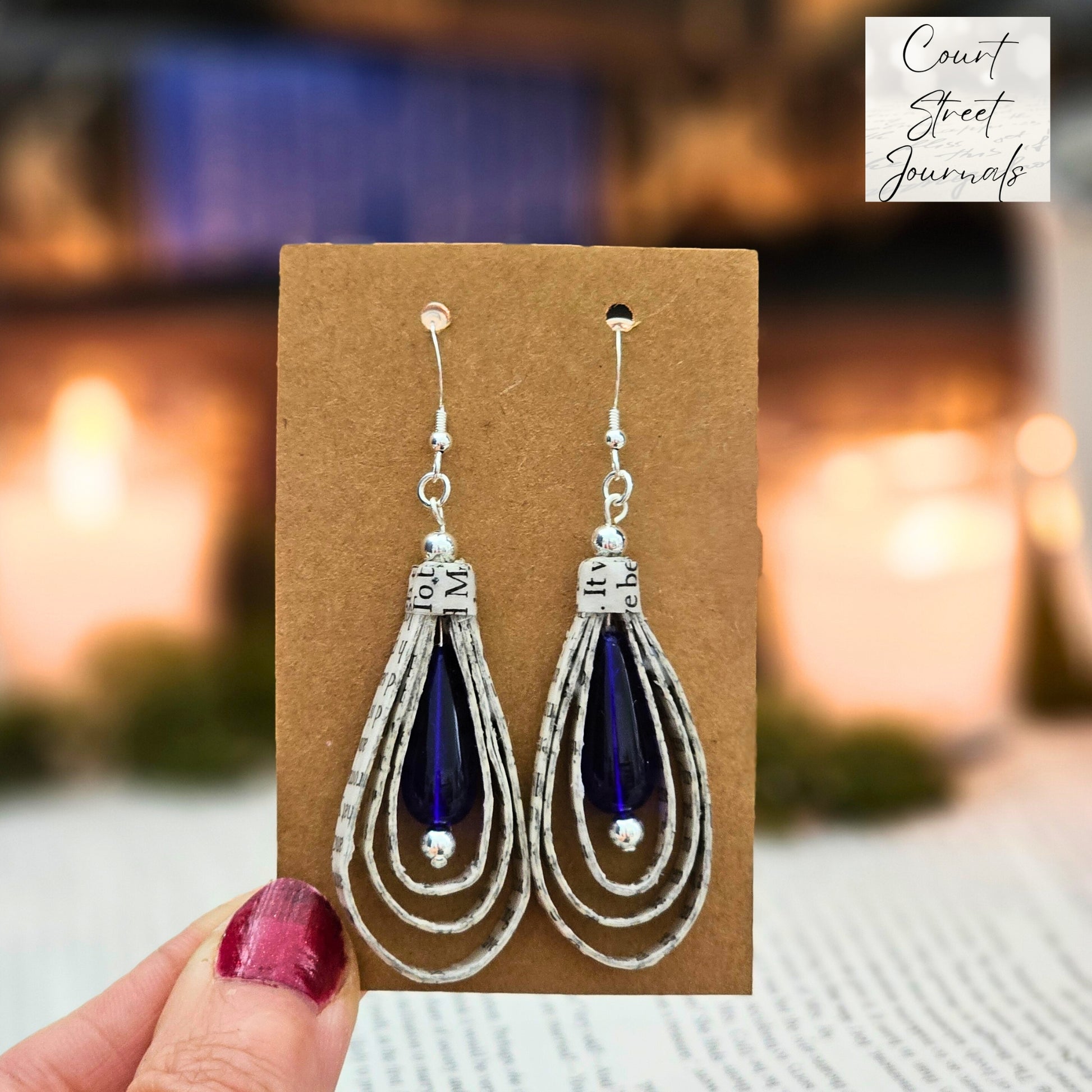 Tear Drop dangle earrings made from upcycled book pages with a blue czech glass tear drop bead accent.  earring is 2.5 inches long.  Sterling silver ear wire.