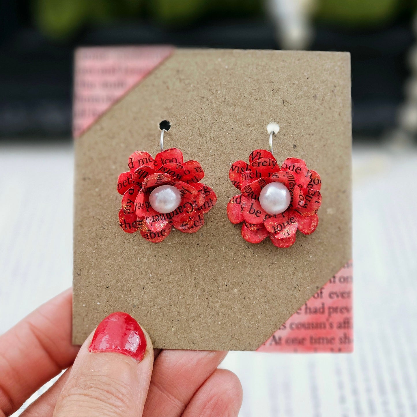 Red Rose Book Page Earrings, Drop Ear Wire made of stainless steel. The center of the rose has a whie acrylic accent. Each pair comes in a gift box adorned with 3 paper roses.
