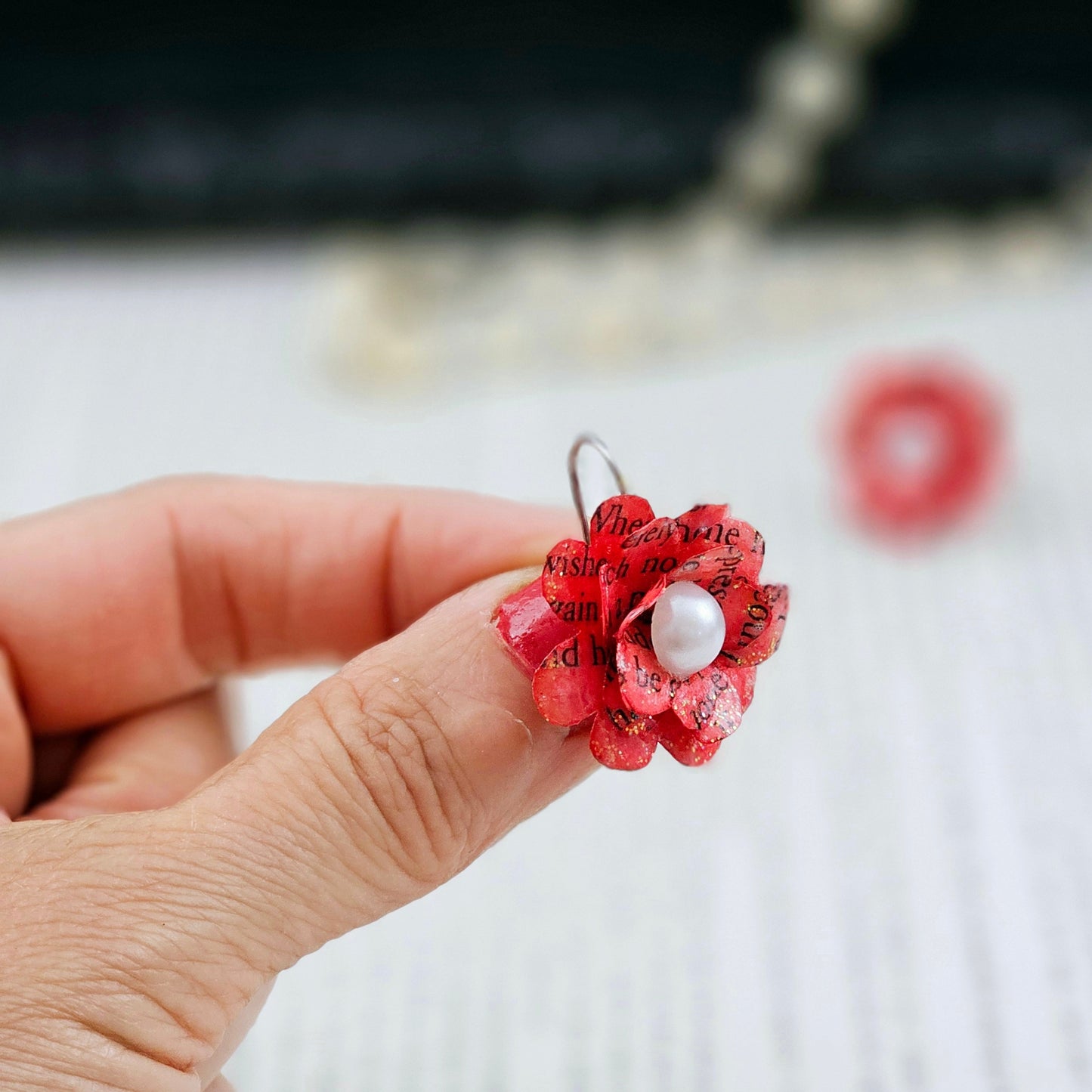 Red Rose Book Page Earrings, Drop Ear Wire made of stainless steel. The center of the rose has a whie acrylic accent. Each pair comes in a gift box adorned with 3 paper roses.