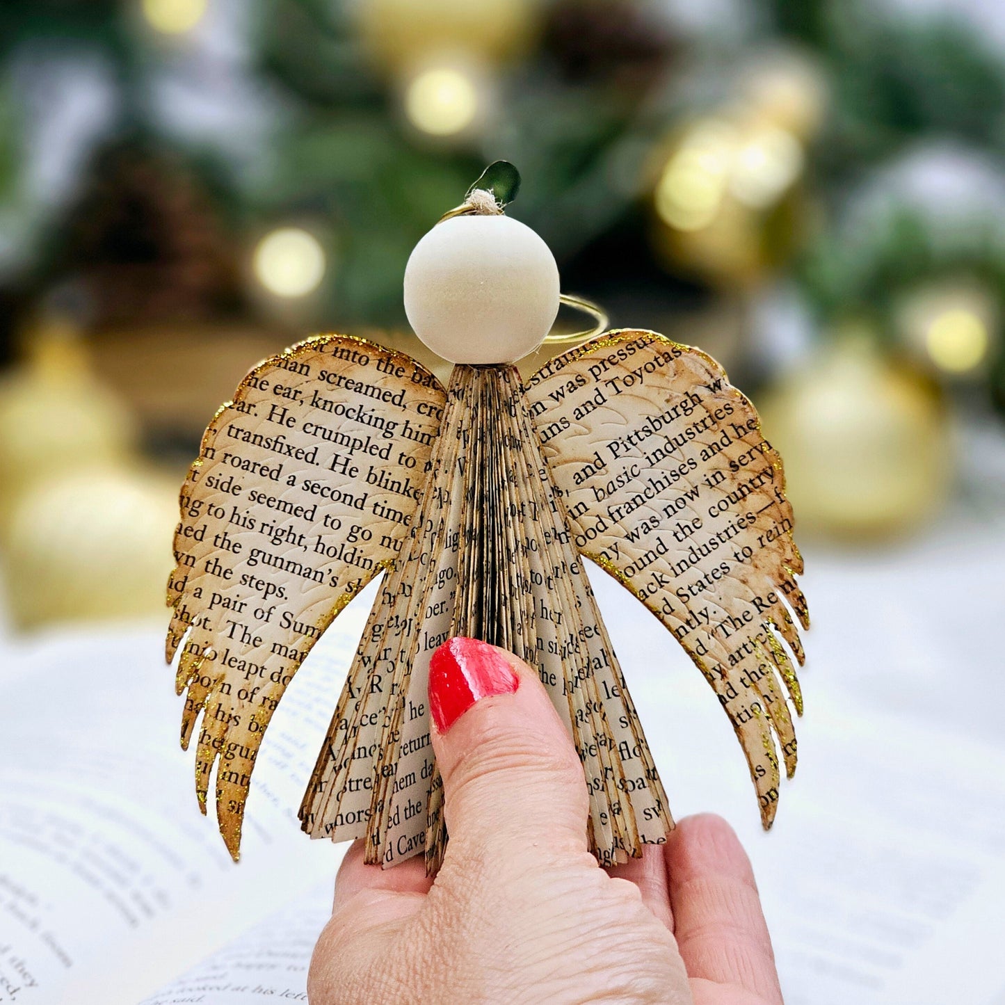 Handmade Boook Page Angel Ornament shown held in a hand.