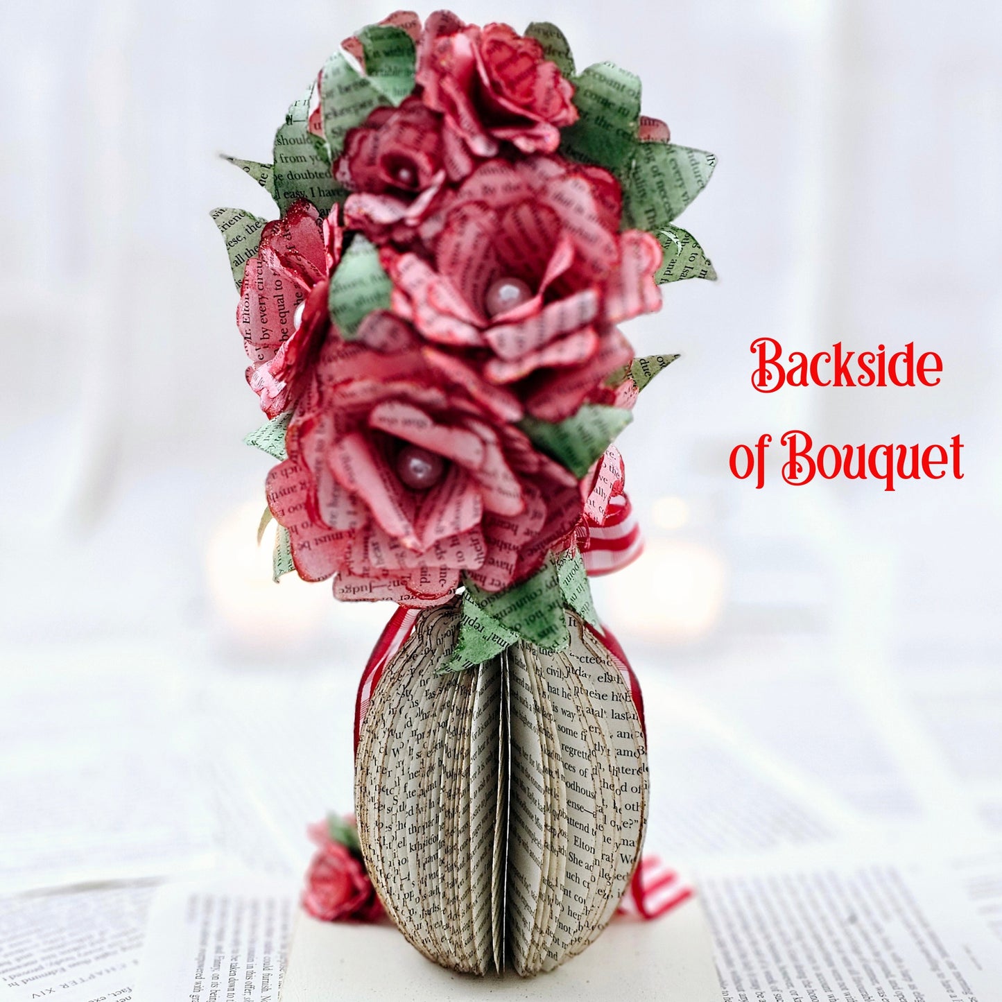 9 inch tall book page flower bouquet, the roses are stained red. The vase is made from book pages . The entire piece sits on a base made from the book cover.