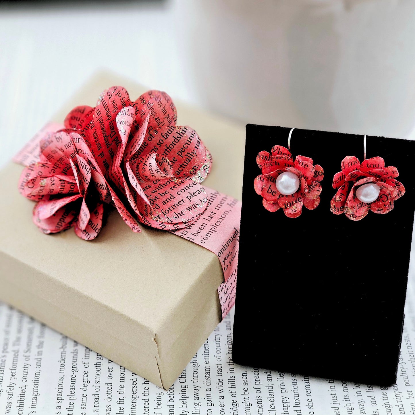 Red Rose Book Page Earrings, Drop Ear Wire made of stainless steel. The center of the rose has a whie acrylic accent. Each pair comes in a gift box adorned with 3 paper roses.