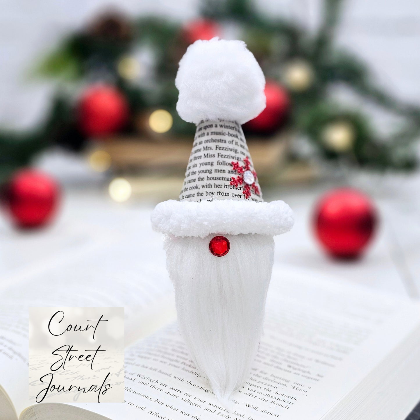 Book Page Gnome Christmast onrament. Artisan made. The body is made of fabric. The hat is made from book pages taken from A Christmas Carol. The hat is lined with fluffy trim and has a white pom on top. The gnome nose is a red acrylic gem .