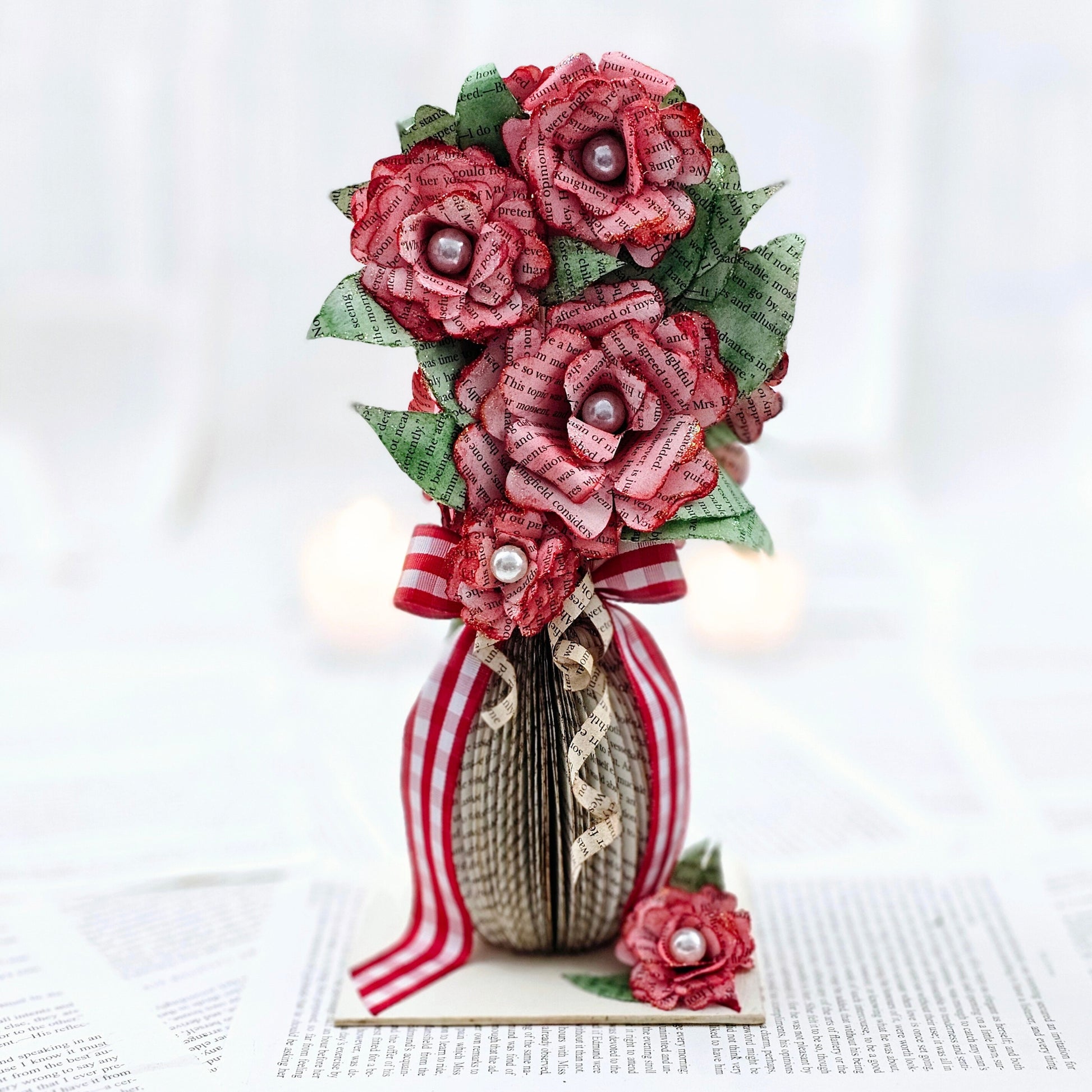 9 inch tall book page flower bouquet, the roses are stained red.  The vase is made from book pages .  The entire piece sits on a base made from the book cover.