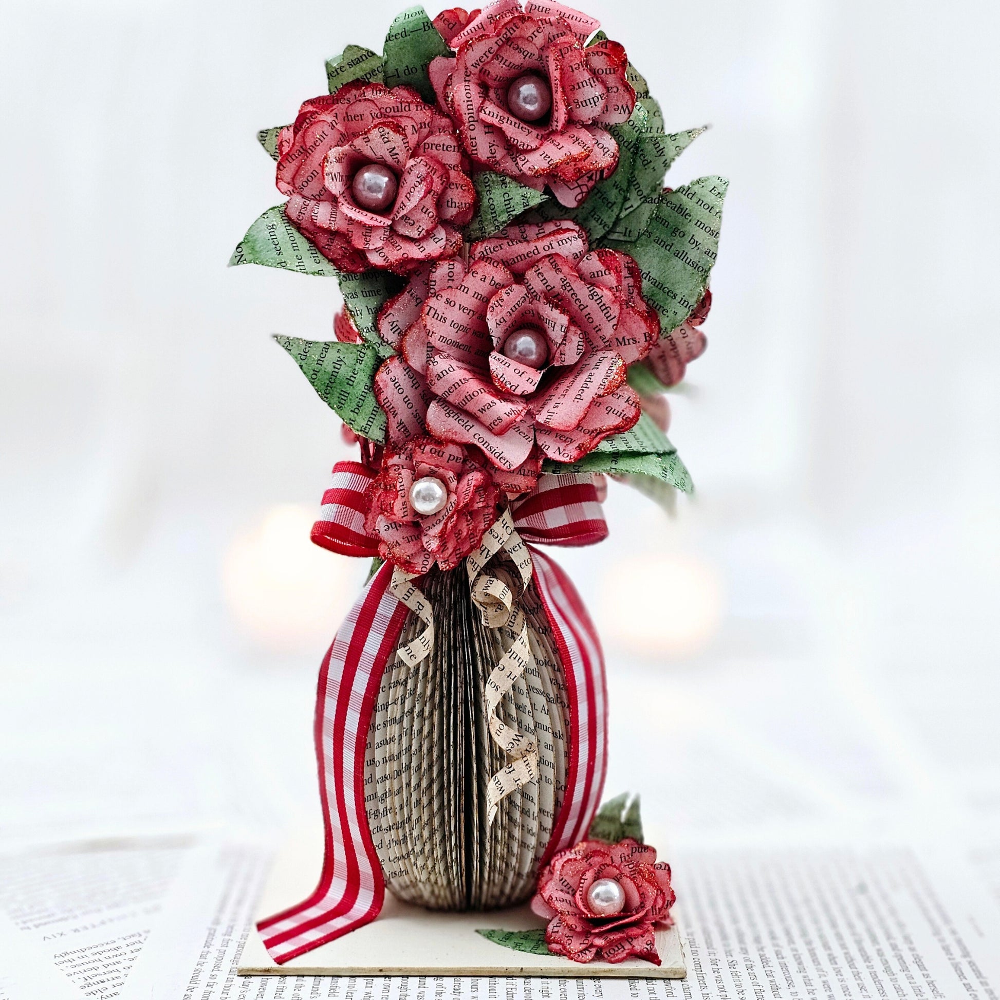 9 inch tall book page flower bouquet, the roses are stained red.  The vase is made from book pages .  The entire piece sits on a base made from the book cover.