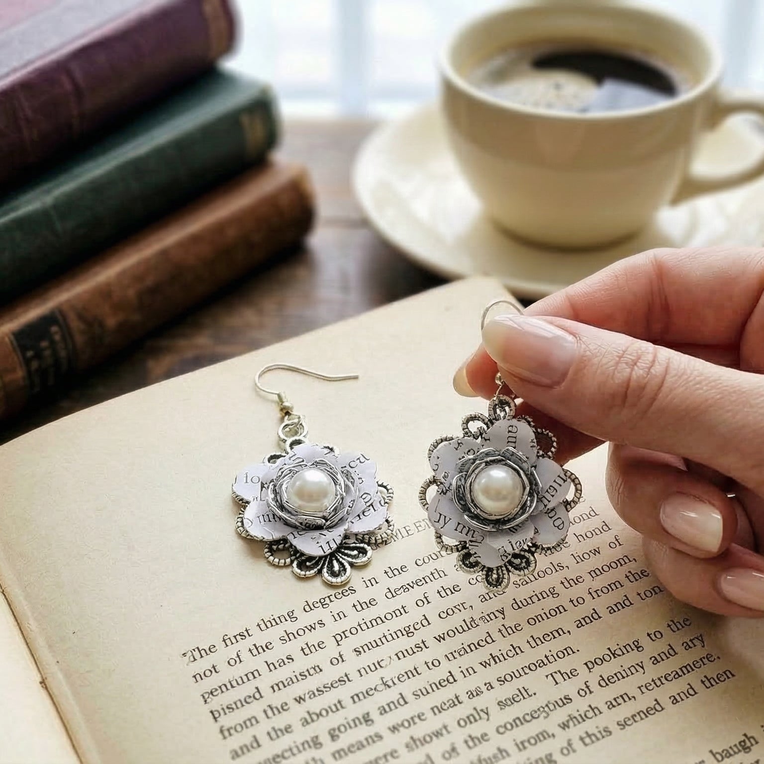 hand held shot of one of the floral book page earrings
