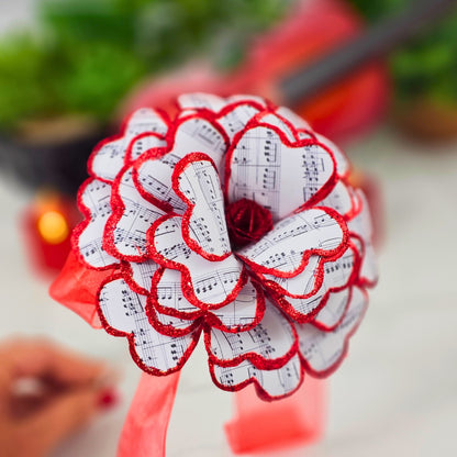 Decorative flower made of red and white paper with music sheet design, held by a hand.