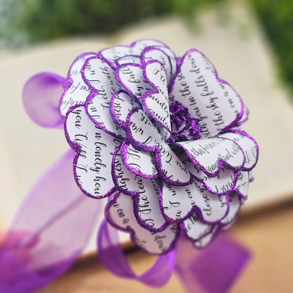 Decorative flower made of paper with purple glittery edges on a blurred background