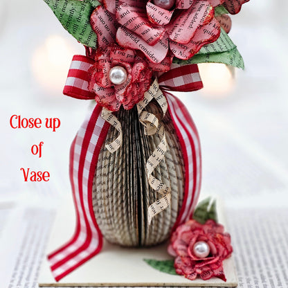 9 inch tall book page flower bouquet, the roses are stained red.  The vase is made from book pages .  The entire piece sits on a base made from the book cover.