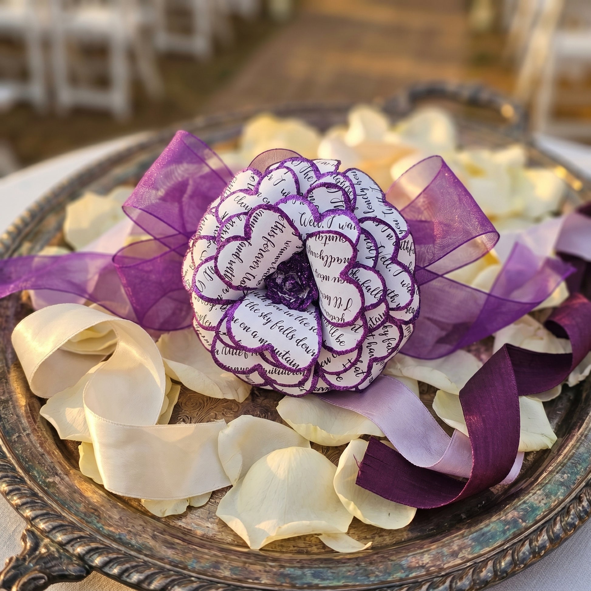 Decorative flower made of paper with purple ribbons on a metallic tray.