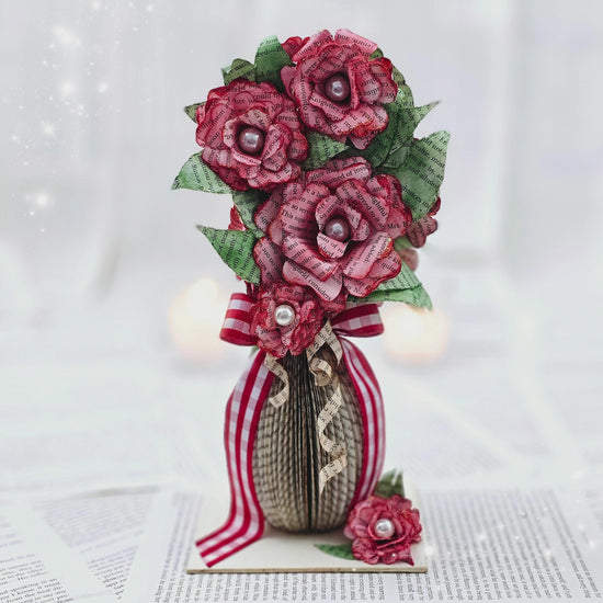 9 inch tall book page flower bouquet, the roses are stained red.  The vase is made from book pages .  The entire piece sits on a base made from the book cover.